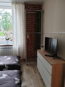 a living room with a television on a dresser with a bed at Sanktuarium Snu Apartments in Głubczyce