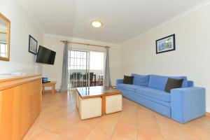 uma sala de estar com um sofá azul e uma televisão em Spectacular Mar a Vista em Portimão