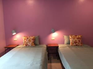 2 Betten in einem Zimmer mit lila Wänden in der Unterkunft Chor Chang House in Chiang Mai