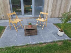 2 chaises et une boîte en bois sur la terrasse dans l'établissement Studio 't Hoveke, à Gullegem