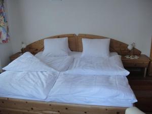 a large wooden bed with white sheets and pillows at Chasa Mezpra/Stephan Jenal Nr. 1 - Ferienwohnung für 2-4 Personen in Compatsch