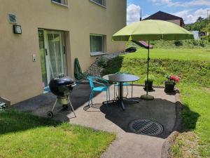 grill i stół z zielonym parasolem w obiekcie Gîte La Broye w mieście Surpierre