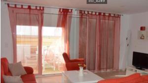 コニル・デ・ラ・フロンテーラにあるBellavista Duplex Superiorのリビングルーム(赤いカーテン、ソファ、テーブル付)