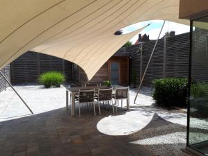 un patio con mesa y sillas bajo una sombrilla en Au Paradis Guesthouse, en Waregem