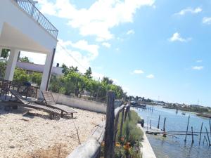 a house with a fence next to a body of water at Torre del Lago in Foce Varano