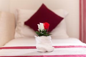 a red and white rose in a white sock vase on a bed at Hotel Villa Nisteri in Limenas