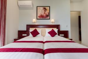 a bedroom with a large bed with red pillows at Hotel Villa Nisteri in Limenas