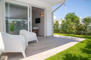 patio con 2 sillas blancas y TV en MARINA PONENTE, en Lido di Jesolo