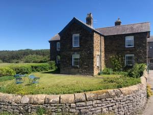a brick house with a stone wall in front of it at Hassop Station Apartment on the Monsal Trail in Bakewell