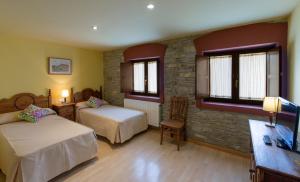 a bedroom with two beds and a stone wall at Hotel Rural Los Cerezos de Yanguas in Yanguas