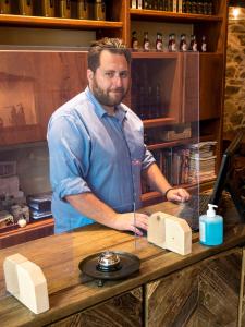 un homme debout derrière un comptoir avec un ordinateur dans l'établissement Gastronomy Hotel Kritsa, à Portariá