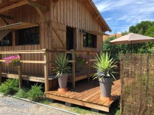a wooden deck with potted plants and an umbrella at Gîte de l'océan, 3 étoiles - Les cabanes océanes, Montalivet in Vendays-Montalivet