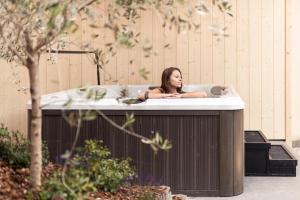 una mujer está sentada en una bañera en Hotel Berghang, en Collepietra