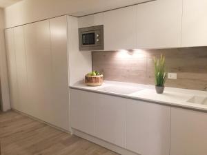 uma cozinha com armários brancos e um vaso de plantas em MARINA PONENTE em Lido di Jesolo