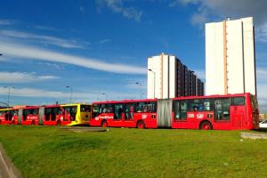 a row of red buses parked in a field at Apartamento en Bogotá muy bien ubicado cerca al aeropuerto in Bogotá