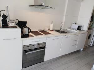 cocina blanca con fregadero y fogones en Le Palais du Tropique appartement vue mer 5é étage avec ascenseur, en Juan-les-Pins