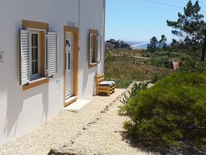 een wit gebouw met ramen en een bank op een heuvel bij Quinta Bogesi in Figueira da Foz