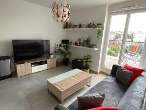 sala de estar con sofá y TV de pantalla plana en 35m2 neuf, plein sud, dernier etage avec terrasse en Noisy-le-Grand