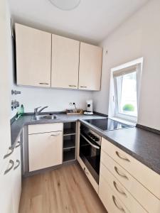 a kitchen with white cabinets and a black stove top oven at Lillys Apartment Kempten in Kempten