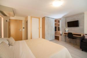 リミニにあるHotel Ricchiの白いベッドとデスクが備わるホテルルームです。