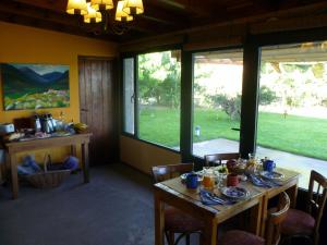 ein Esszimmer mit einem Tisch und einigen Fenstern in der Unterkunft La Calandria Casa de Campo in Puerto Madryn