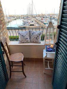 een balkon met een tafel en een stoel en uitzicht op een haven bij FRA EM DORIA in Nettuno