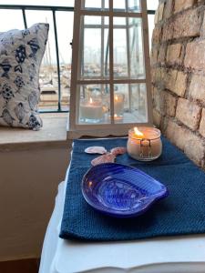 een blauwe plaat en kaars op een tafel met een raam bij FRA EM DORIA in Nettuno