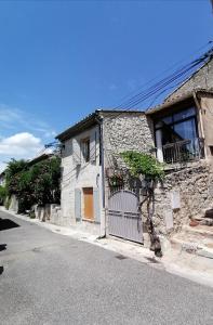 a stone building with a gate on the side of a street at Maison de charme pittoresque Villeneuve lez Avignon in Villeneuve-lès-Avignon