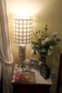 un tavolo con lampada, orologio e vaso di fiori di The Old Deer House a Bodmin