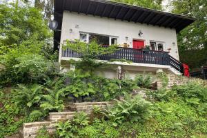 Cette maison dispose d'un balcon avec une porte rouge. dans l'établissement The Vianden Cottage - Charming Cottage in the Forest, à Vianden