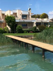 a wooden bridge over a river in front of a building at Lake Front Apartment - Direct Lake Access in Sirmione