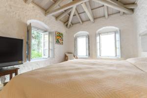 a white bedroom with a large bed and windows at Vita Real Estate in Hydra