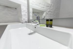 a white bathroom with a sink and a mirror at Vita Real Estate in Hydra +10 photos