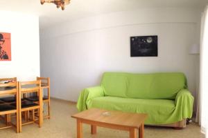 un soggiorno con divano verde e tavolo di Apartamento en Playa de Levante Vistas impresionantes a Benidorm