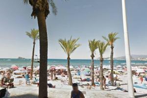 un gruppo di persone su una spiaggia con palme di Apartamento en Playa de Levante Vistas impresionantes a Benidorm
