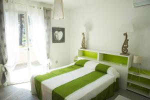 a bedroom with a green and white bed and a window at Nicola's Apartments in Marina di Campo