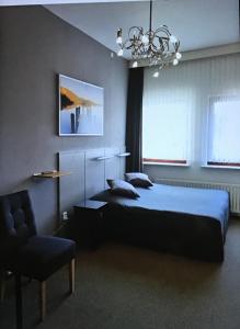 a bedroom with a bed, chair, lamp and window at Hotel Heynen in Valkenburg