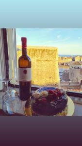 eine Flasche Wein und ein Teller mit Essen neben einem Fenster in der Unterkunft Apartman Roseta in Dubrovnik