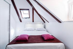 a white bed with two purple pillows on it at Apartman Roseta in Dubrovnik