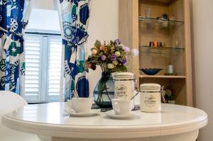 a white table with two cups and a vase with flowers at Apartman Roseta in Dubrovnik