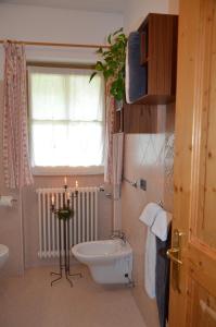 łazienka z toaletą, oknem i świecą w obiekcie B&B Primavera w mieście Spormaggiore
