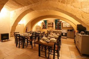 a dining room with tables and chairs and a kitchen at Ta' Matmura Farmhouse in Għarb