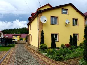 une maison jaune avec deux fenêtres et une allée en briques dans l'établissement Садиба Святослав, à Skhidnitsa