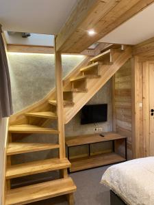a bedroom with wooden stairs with a tv and a bed at willa ella in Zakopane