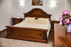 a bedroom with a large wooden bed with two night stands at Casa de sub deal in Bîltişoara
