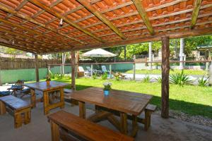 deux tables et chaises en bois sous une pergola en bois dans l'établissement Pousada Sítio Olho D'Água, à Bombinhas