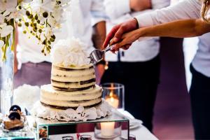 a person cutting a wedding cake with a knife at Villa Valery - pajūrio dvasia dvelkianti oazė in Kupriai