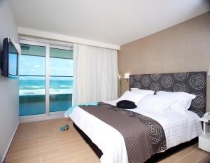 a bedroom with a large bed and a large window at West All Suites Hotel Ashdod in Ashdod