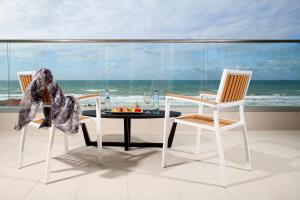 uma sala de jantar com uma mesa e duas cadeiras e o oceano em West All Suites Hotel Ashdod em Ashdod