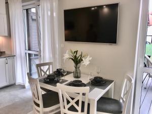 a dining room table with chairs and a television on a wall at Apartamenty Porto Eli in Rowy